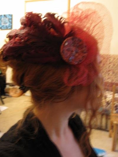 Large burgandy curled feathers, maroon netting and large ceramic button